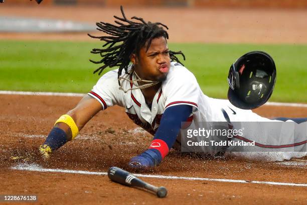 Ronald Acuna Jr. #13 of the Atlanta Braves slides into home to score on a double in the first inning of an MLB game against the Miami Marlins at...