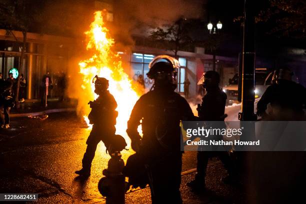 Portland police walk past a fire started by a Molotov cocktail thrown at police on September 23, 2020 in Portland, United States. Violent protests...
