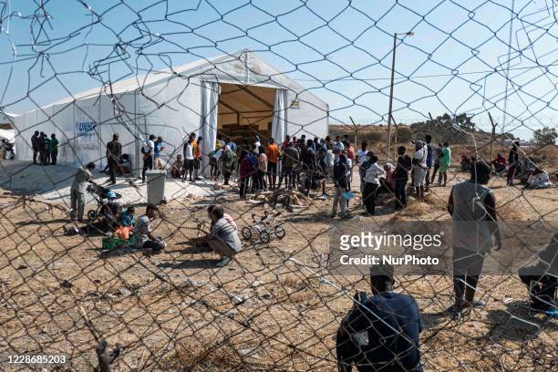 The New Temporary Refugee Camp in Kara Tepe - Mavrovouni with large white tents having the UNHCR or UNICEF logo and asylum seekers waiting in line...