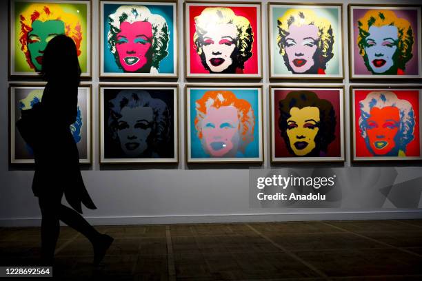 Silhouette of a woman passing by the 1967 ten-screenprint portfolio Marilyn Monroe by American visual artist and producer Andy Warhol on display...