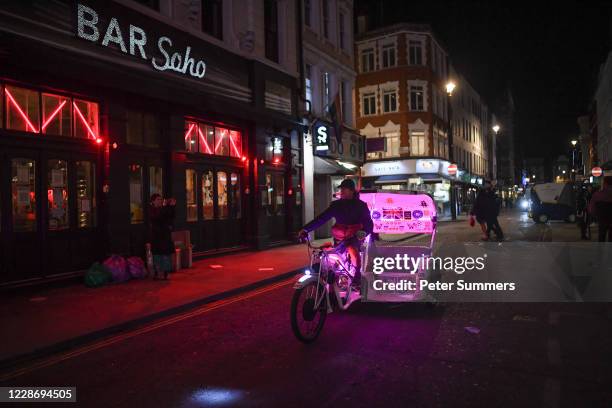 Rickshaw taxi rides past in Soho on September 24, 2020 in London, England. Pubs, cafes and restaurants will have to shut at 10pm every night under...