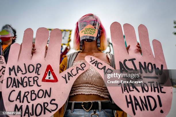 Environmental activists, wearing facemasks and face shields to protect against COVID-19, take part in a rally coinciding with global protests on the...