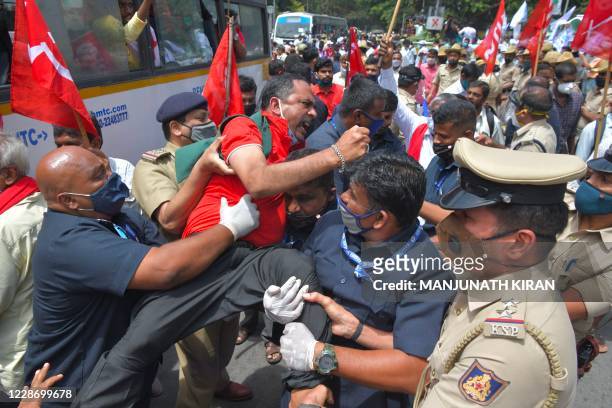 Police personnel detain an activist from a farmers rights organisation during a protest following the recent passing of agriculture bills in the Lok...