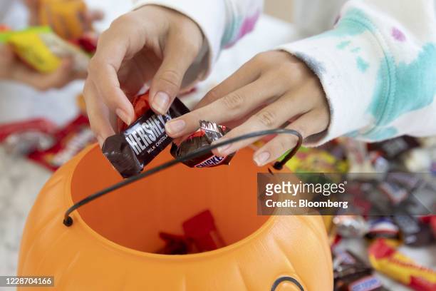 Child holds a Mars Inc. Brand Snickers bar and a Hershey Co. Brand milk chocolate bar in an arranged photograph taken in Tiskilwa, Illinois, U.S., on...