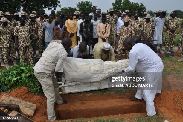 Nigerian soldiers and relatives look on as the body of a victim of the attack on vehicles carrying Borno governor Babagana Umara Zulum near the town...