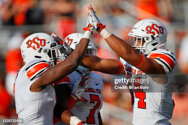 Linebacker Calvin Bundage gets congratulated by linebacker Amen Ogbongbemiga and defensive end Trace Ford of the Oklahoma State Cowboys after sacking...