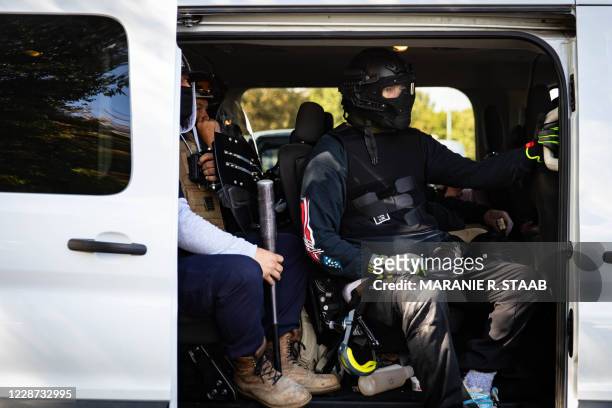 Men in riot gear sit in a van as several hundred members of the Proud Boys and other similar groups gathered for a rally at Delta Park in Portland,...