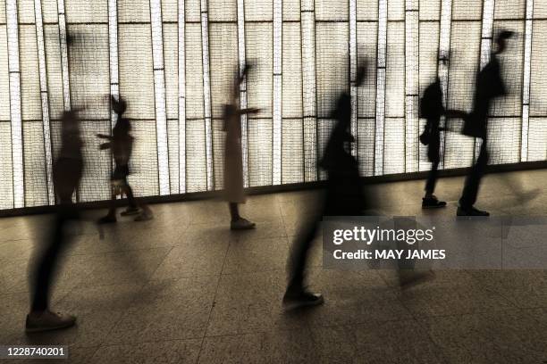 People are seen silhouetted against a storefront display in Hong Kong on September 27, 2020.