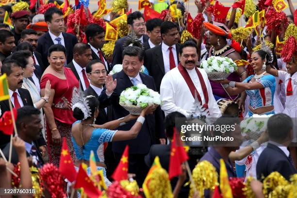 Chinese President Xi Jinping acknowledges the reception watched by Sri Lankan President Mahinda Rajapaksa as they walk during a welcome ceremony at...