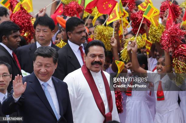 Chinese President Xi Jinping acknowledges the reception watched by Sri Lankan President Mahinda Rajapaksa as they walk during a welcome ceremony at...