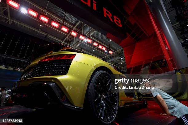 Chinease man wear protective masks as he look a new Audi R8 car is during the 2020 Beijing International Automotive Exhibition at China International...