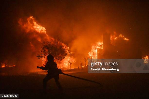 Firefighter carries a hose as buildings burn in the Skyhawk Park neighborhood of East Santa Rosa during the Shady Fire in Sonoma County, California,...