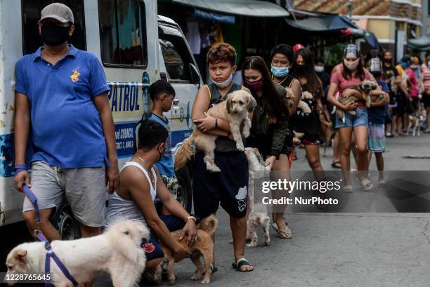 People carrying their pets queue to avail of free rabies vaccine and deworming in celebration of World Rabies Day on September 28, 2020 in Manila,...