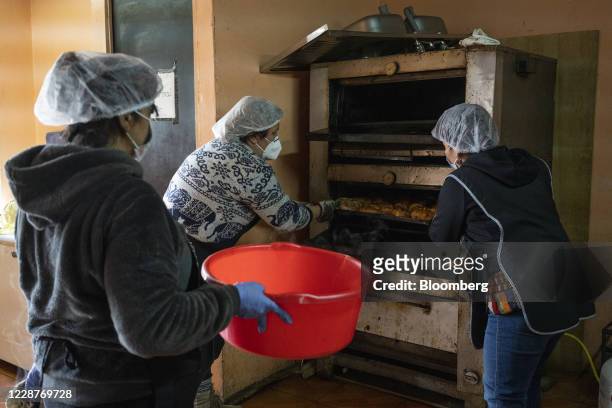 Social workers cook roasted chicken at a "olla comun" community kitchen in the Lo Hermida neighborhood of Santiago, Chile, on Monday, Aug. 17, 2020....