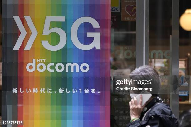 Pedestrian holding a smartphone walks past an NTT Docomo Inc. Store in Tokyo, Japan, on Tuesday, Sept. 29, 2020. Nippon Telegraph & Telephone Corp.s...