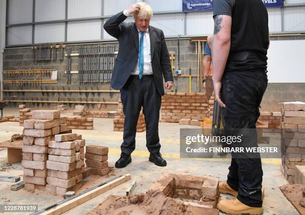 Britain's Prime Minister Boris Johnson reacts as lays bricks whilst talking with students during his visit to Exeter College in Exeter, southwest...