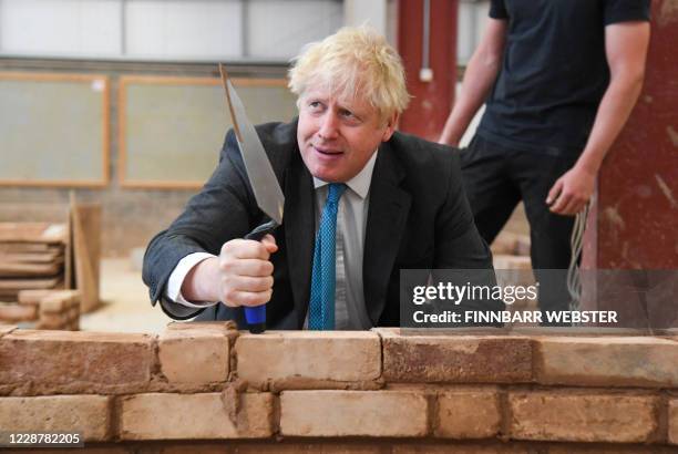 Britain's Prime Minister Boris Johnson reacts as lays bricks whilst talking with students during his visit to Exeter College in Exeter, southwest...