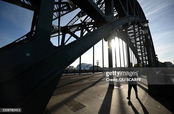 Pedestrian walks across the Tyne Bridge, spanning the River Tyne in Newcastle, northeast England on September 29 after tighter restrictions were put...
