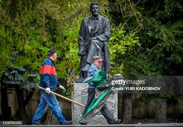 Two municipal workers walk past a monument to famous Russian writer Anton Chekhov in the town of Chekhov, some 70 km outside Moscow, on September 29,...