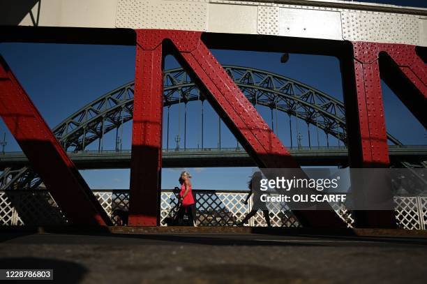 Pedestrians walk across the Swing Bridge, near the Tyne Bridge in Newcastle, northeast England on September 29 after tighter restrictions were put in...