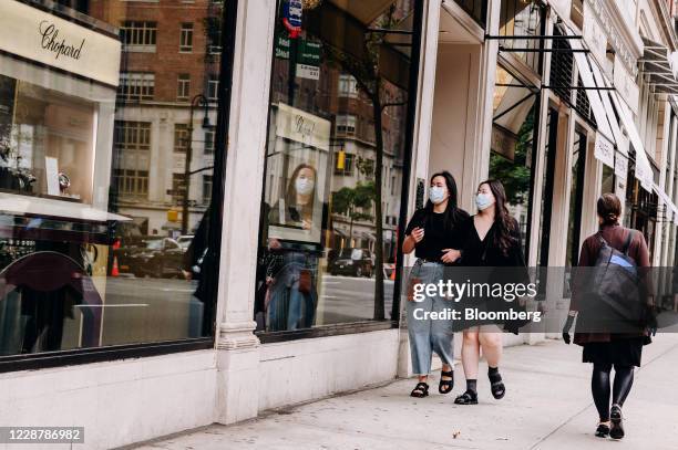 Pedestrians wearing protective masks pass in front of the Chopard jewelry store on Madison Avenue in New York, U.S., on Saturday, Sept. 26, 2020. The...
