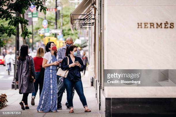 Pedestrians wearing protective masks wait to enter the Hermes store on Madison Avenue in New York, U.S., on Saturday, Sept. 26, 2020. The pandemic...