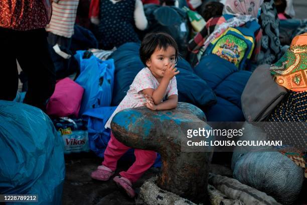 Child suchs her thumb as refugees from the islands of Lesbos, Chios, Samos, Kos and Leros wait to board buses after disembarking at the port of...