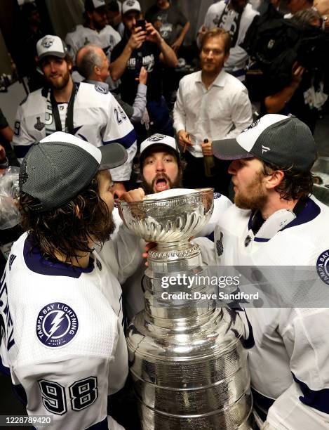 Mikhail Sergachev, Nikita Kucherov and Andrei Vasilevskiy of the Tampa Bay Lightning celebrate with the Stanley Cup in the locker room after the...