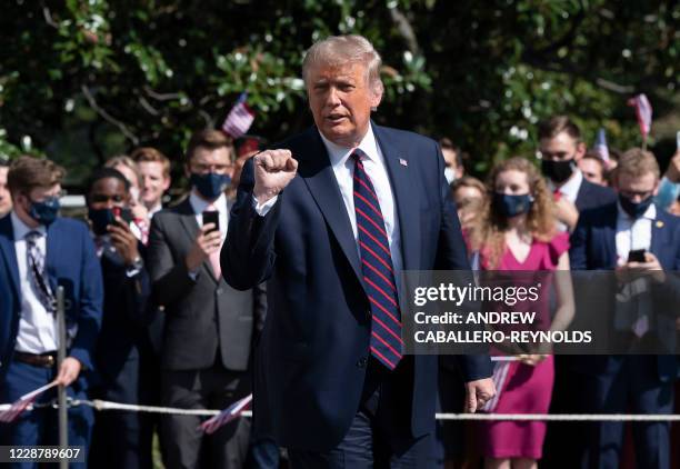 President Donald Trump gestures as White House interns look on, as the President walks to Marine One to depart from the South Lawn of the White House...