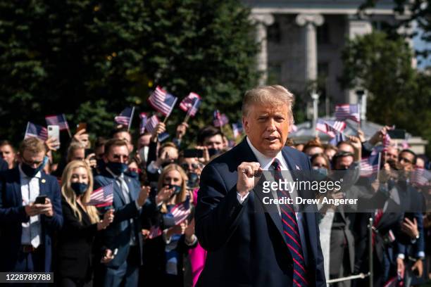 President Donald Trump gestures as White House interns cheer him on as he leaves the White House residence for Marine One on the South Lawn of the...