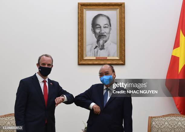 Britain's Foreign Secretary Dominic Raab elbow bumps with Vietnam's Prime Minister Nguyen Xuan Phuc under the portrait of the late Ho Chi Minh,...