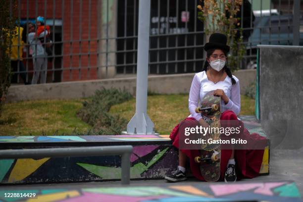 Woman dressing the traditional clothes of a 'cholita' is seen holding a skateboard during a skate festival on September 30, 2020 in La Paz, Bolivia....