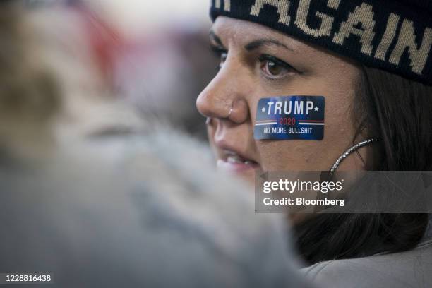 An attendee wears a sticker on her face while waiting for U.S. President Donald Trump to arrive at a 'Make America Great Again' rally in Duluth,...