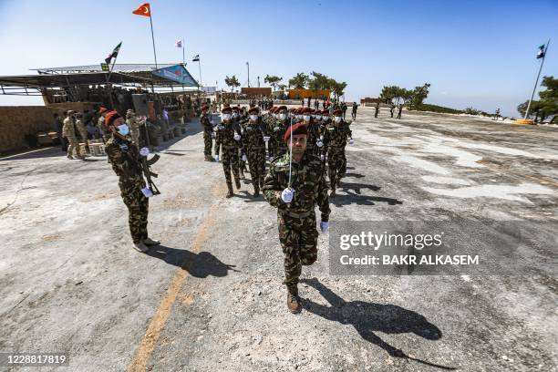 Turkish-backed Syrian rebel fighters, mask-clad due to the COVID-19 coronavirus pandemic, march in formation during a military parade marking the...