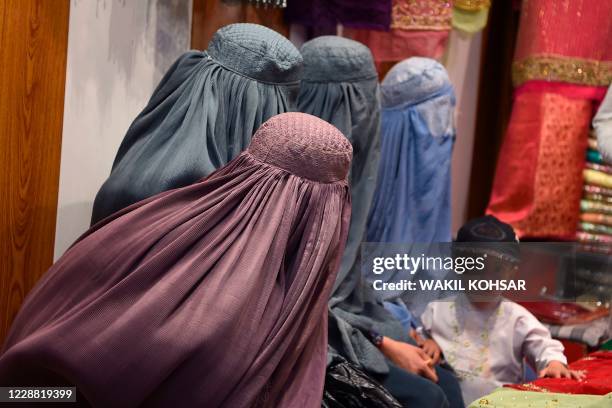 Burqa-clad women shop at a women's clothing store in Kandahar on October 1, 2020.