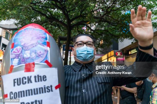 An impersonator of North Korean leader Kim Jung Un makes a gesture as he hold a plastic inflatable missile with a illustration of China's Premier Xi...