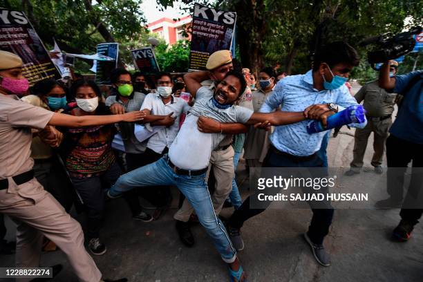 Police personnel detain a student during a protest following accusations of Indian Police forcibly cremating the body of a 19-year-old woman victim,...