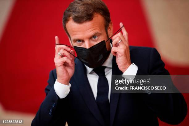 French President Emmanuel Macron takes off his face mask as he arrives for a European Union summit at the European Council Building in Brussels on...