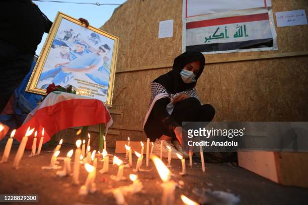 Woman lit a candle in memory of those who lost their lives during a protest as Iraqis gather to mark 1st anniversary of Iraqi anti-government...