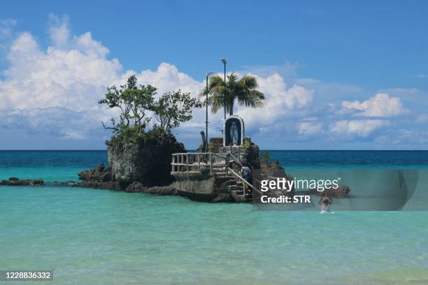 In this photo taken on October 1 residents visit the groto of the Virgin Mary at Willy's rock on a beach in Borocay, central Philippines. -...