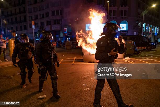 Riot police officers are seen passing in front of a burning barricade of garbage containers in Plaza Catalunya as pro-independence demonstrators...