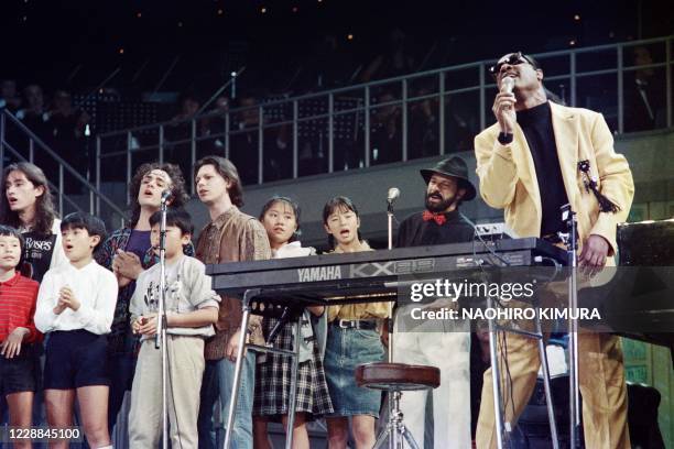 Pop-star Stevie Wonder leads Japanese children and other popular song stars from the world as they sing "Children of the world" at the closing of the...