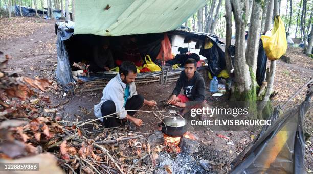 Migrants from Bangladesh, awaiting to enter Croatia, cook and warm up near a fire at an improvised camp in the woods, hundreds of meters away from...