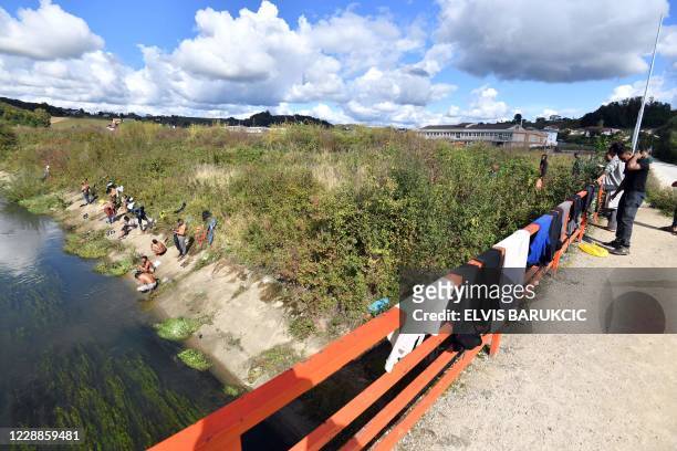 Migrants from Bangladesh, who have repeatedly attempted to enter Croatia, bathe and dry their clothes in a creek, hundreds of meters away from...