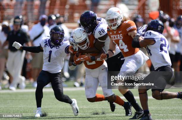 Texas Longhorn RB Roschon Johnson is tackled by TCU Horned Frog defenders Trevius Hodges-Tomlinson and La'Kendrick Van Zandt during game featuring...