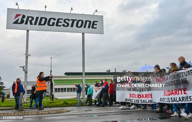 People wearing face masks hold banners reading "No to the Bridgestone closure, solidarity with the employees" as they take part in a demonstration to...