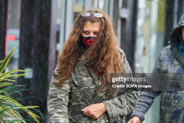 Woman wearing a face mask on a wet and windy day caused by Storm Alex.