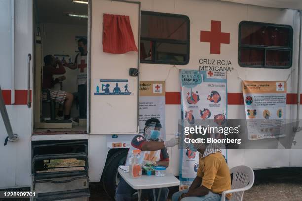 Member of the Red Cross takes the temperature of a Central American migrant outside La 72 migrant shelter in the town of Tenosique, Tabasco state,...