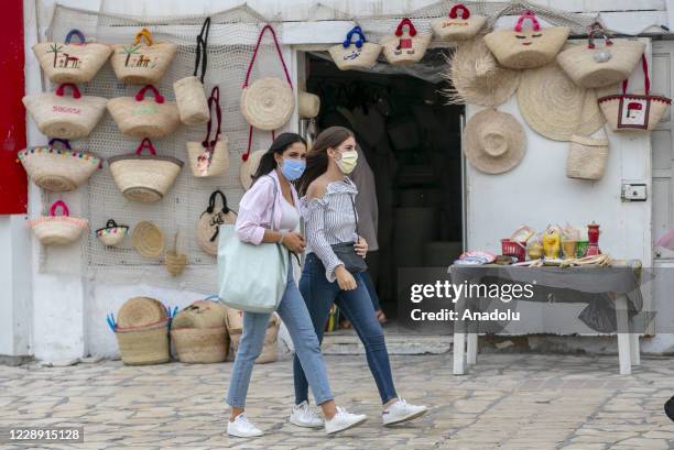 Tunisians and tourists wear masks as a precaution against the novel coronavirus pandemic as they go out in Soussa, Tunisia on October 05, 2020. As...