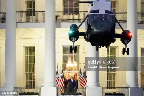 President Donald Trump stands on the Blue Room Balcony as Marine One takes off from the South Lawn of the White House on October 5, 2020 in...